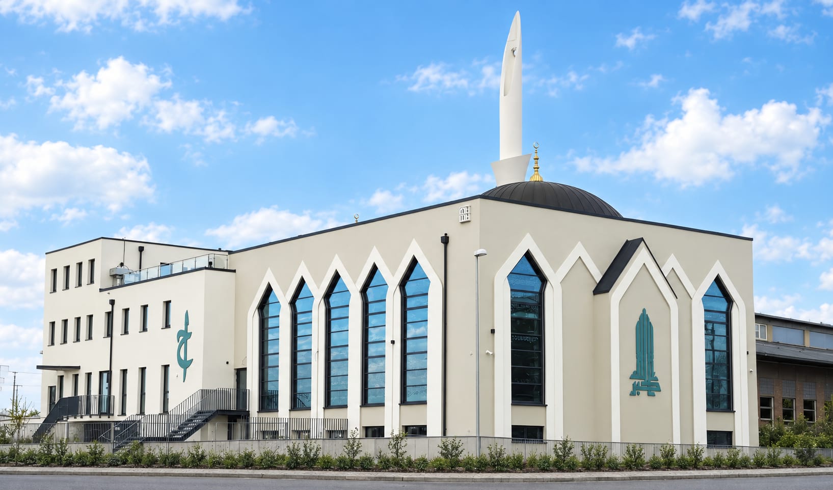 Die Moschee mit hellen Fassaden, hohen Bogenfenstern und Minarett unter blauem Himmel
